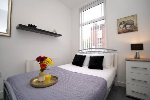 Un dormitorio con una cama y una bandeja con flores. en Gordon House - 4Bed Coventry City Centre Oasis with Free Parking en Coventry