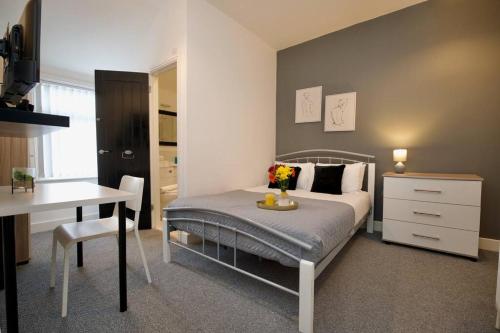 a bedroom with a bed and a table and a desk at Gordon House - Fully Furnished, TVs in All Rooms, Netflix, Walk to City Centre in Coventry