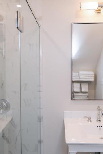 a bathroom with a shower and a sink and a mirror at The Bell Inn in Peabody