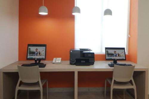 a desk with two computer monitors and two chairs at City Express Junior by Marriott Tijuana Otay in Tijuana