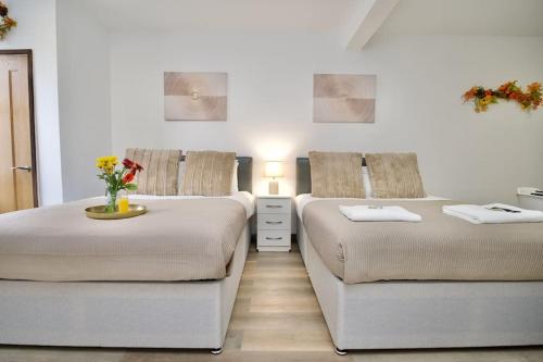 two beds in a white room with flowers on a table at Matlock Studio 1 - Coventry in Coventry