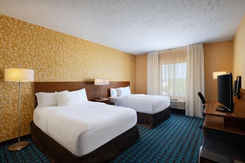 a hotel room with two beds and a flat screen tv at Fairfield Inn & Suites by Marriott Lincoln Airport in Lincoln