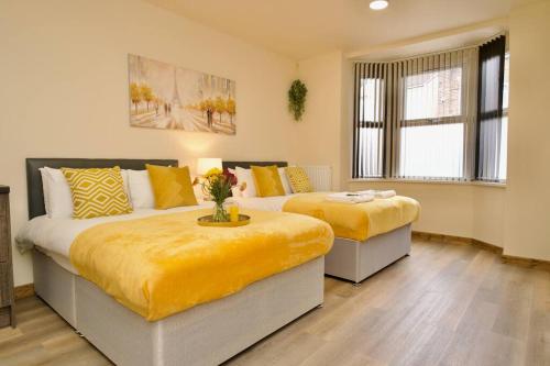 a bedroom with two beds with yellow sheets at Matlock Studio 2 – Coventry in Coventry