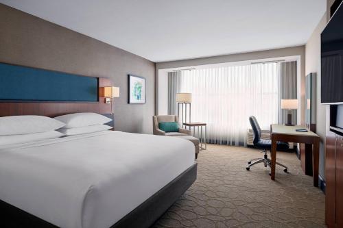 a hotel room with a large bed and a desk at Delta Hotels by Marriott Milwaukee Northwest in Menomonee Falls