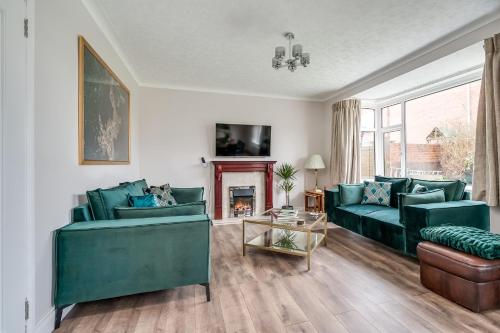 a living room with two green couches and a fireplace at Cavehill View - Elegant 4-bedroom detached house in great location with free parking in Belfast