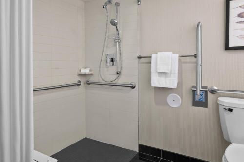 a bathroom with a shower and a toilet at Delta Hotels by Marriott Milwaukee Northwest in Menomonee Falls