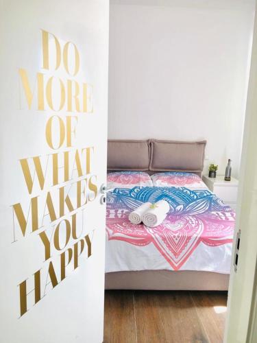 a bedroom with a bed with a do more of what makes you happy sign at Happy Place, Boa Vista, Salrei in Sal Rei