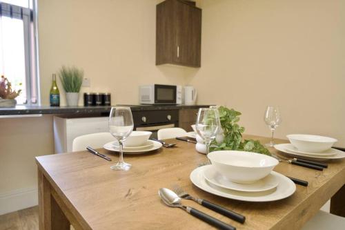 a wooden table with plates and bowls and wine glasses at Matlock Studio 3 – Coventry in Coventry