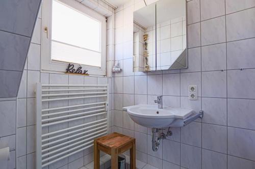 Baño blanco con lavabo y espejo en App-Hanna, en Westerland