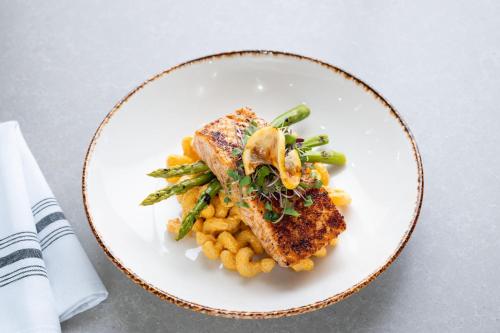 a white plate with a piece of fish and pasta at Delta Hotels by Marriott Wichita Falls Convention Center in Wichita Falls