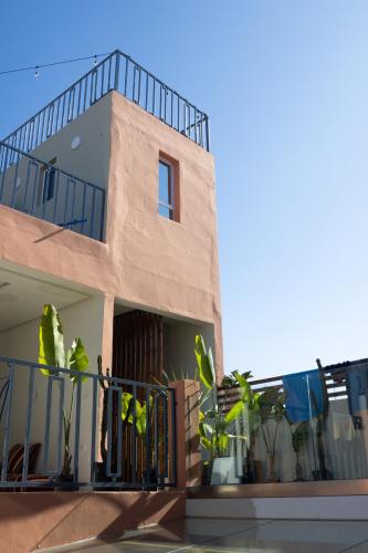 a building with a balcony with plants on it at Playa Del Sol Surf House in Tamraght Ouzdar