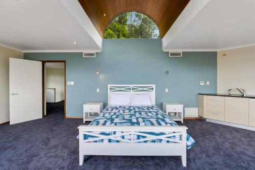 a bedroom with a white bed and a blue wall at Bayview Panorama - Paihia Holiday Home in Paihia
