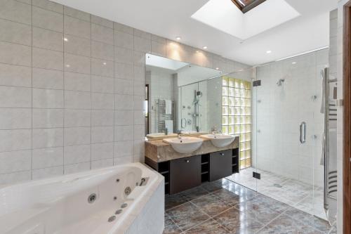 a bathroom with two sinks and a tub and a shower at Bayview Panorama - Paihia Holiday Home in Paihia