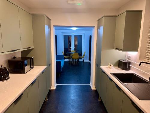 uma cozinha com armários brancos e uma sala de jantar em Dunedin Heights em Londres