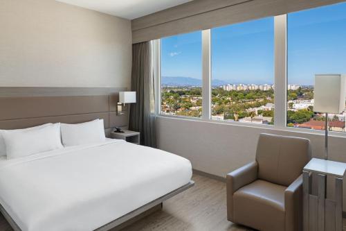 1 dormitorio con cama, silla y ventana grande en AC Hotel by Marriott Beverly Hills, en Los Ángeles