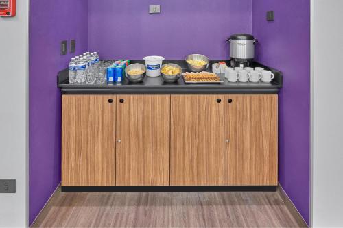 a counter with food and drinks on a purple wall at City Express by Marriott Tapachula in Tapachula