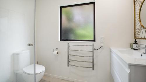 a bathroom with a toilet and a television on the wall at Hibiscus Hideaway - Orewa Beach Holiday Home in Orewa