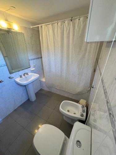 a white bathroom with a toilet and a sink at Duplex al Golf Sierra de los Padres in Sierra de los Padres