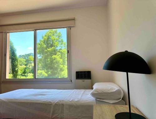 a bedroom with a bed and a large window at Duplex al Golf Sierra de los Padres in Sierra de los Padres