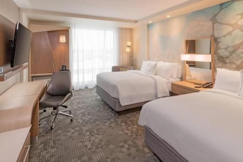 a hotel room with two beds and a desk at Courtyard by Marriott Burlington-Oakville in Burlington