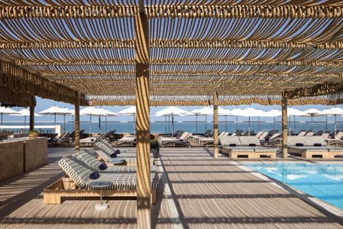 a pool with chairs and umbrellas next to a pool at Sheraton Grand Tel Aviv in Tel Aviv