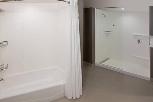 La salle de bains blanche est pourvue d'une douche et d'une baignoire. dans l'établissement Courtyard by Marriott Burlington-Oakville, à Burlington