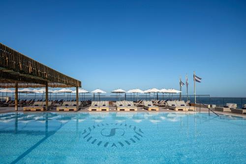 a swimming pool with chairs and umbrellas on the beach at Sheraton Grand Tel Aviv in Tel Aviv