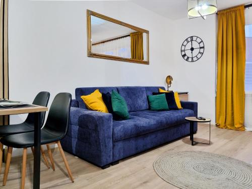 a living room with a blue couch with colorful pillows at CLASSY APARTMENTS - Gdynia - Na Wzgórzu Deluxe in Gdynia