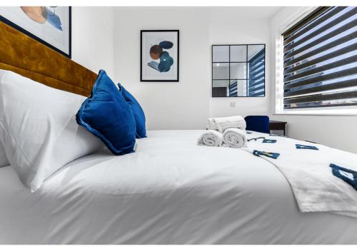 um quarto com uma grande cama branca com almofadas azuis em Modern Apartment Where Everything Just Works! em Londres