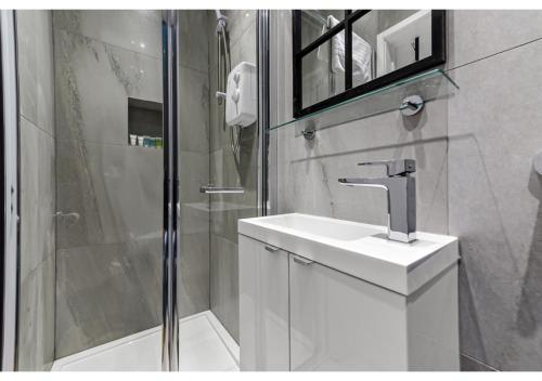uma casa de banho branca com um lavatório e um chuveiro em Modern Apartment Where Everything Just Works! em Londres