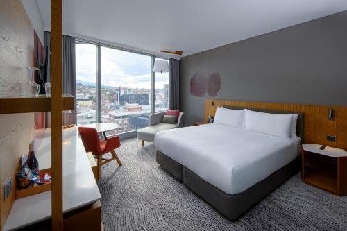 a hotel room with a bed and a large window at Crowne Plaza Hobart by IHG in Hobart