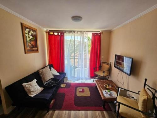 a living room with a couch and red curtains at Departamento en Arica in Arica