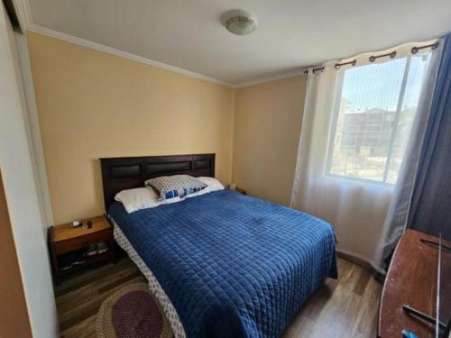 a bedroom with a bed with a blue blanket and a window at Departamento en Arica in Arica