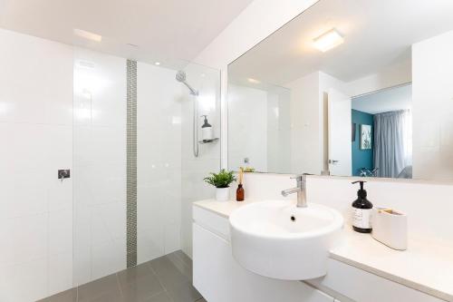 y baño blanco con lavabo y ducha. en Waterline 302, en Forster