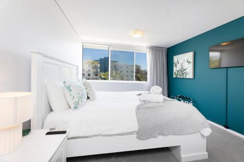1 dormitorio con cama blanca y ventana en Waterline 302, en Forster