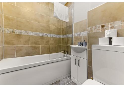 uma casa de banho com uma banheira, um WC e um lavatório. em Stunning Family Home - Sleeps 11 em Londres