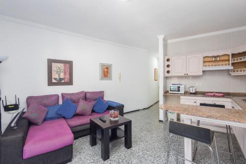 ein Wohnzimmer mit einem lila Sofa und einer Küche in der Unterkunft Ligthbooking Arguineguin playa Lola in Arguineguín