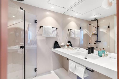 a white bathroom with two sinks and a shower at LUX Hotel in Lillestrøm