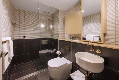 a bathroom with a white toilet and a sink at Brady Hotels Central Melbourne in Melbourne