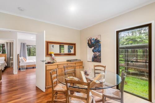 a dining room with a glass table and chairs at Cockatoo Hideaway- Cabin in Montville