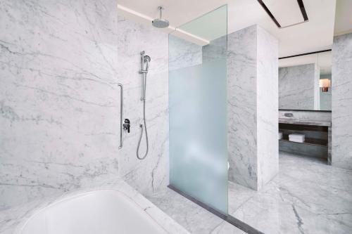 La salle de bains est pourvue d'une douche avec une porte en verre. dans l'établissement Sheraton Grand Jakarta Gandaria City Hotel, à Jakarta