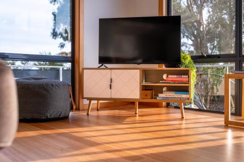 a living room with a flat screen tv on a cabinet at Beachcomber in Coles Bay