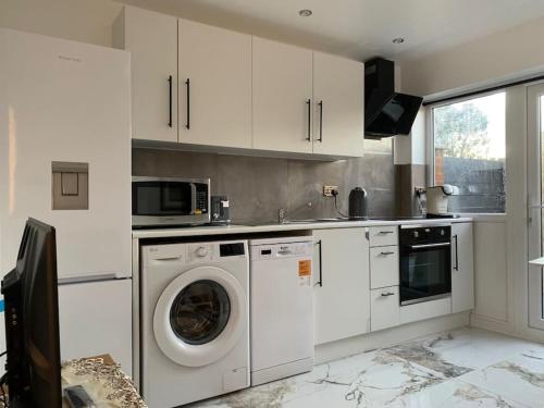 a kitchen with a washing machine and a microwave at Apartment C, a one bedroom Flat in south London in Carshalton