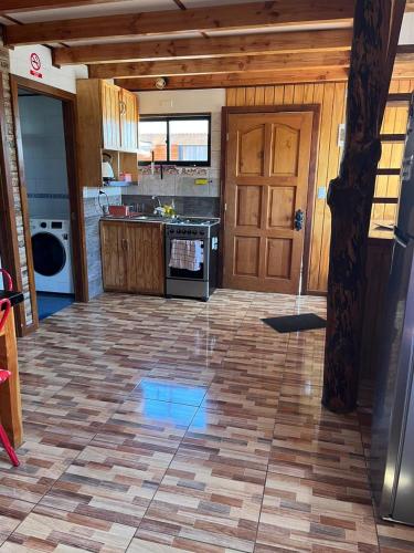 a kitchen with a wooden door and a tile floor at Cabañas "El Cazador" in Futaleufú