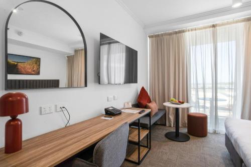 een hotelkamer met een bureau en een bed bij Quest Mackay on Gordon in Mackay