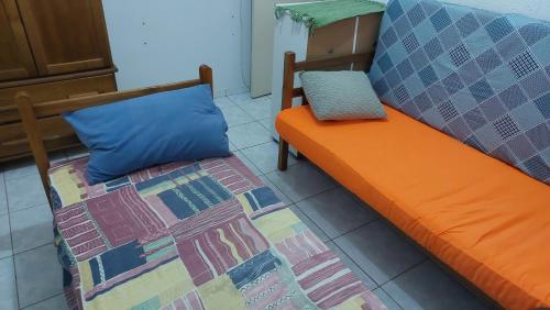 ein orangefarbenes Bett und ein blaues Kissen in einem Zimmer in der Unterkunft Doce Lar in Peruíbe