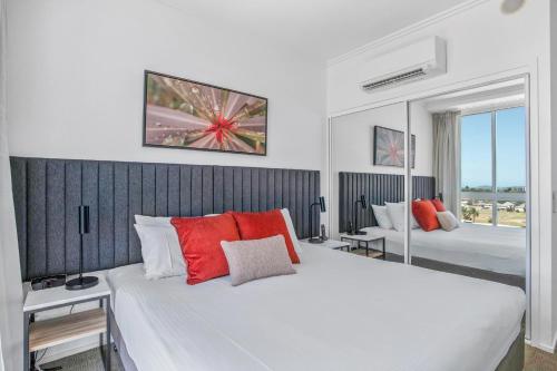 a bedroom with a large white bed with red pillows at Quest Mackay on Gordon in Mackay