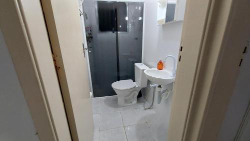 a bathroom with a toilet and a shower and a sink at Doce Lar in Peruíbe