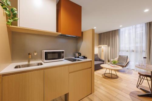 a kitchen with a sink and a living room at Brady Hotels Central Melbourne in Melbourne