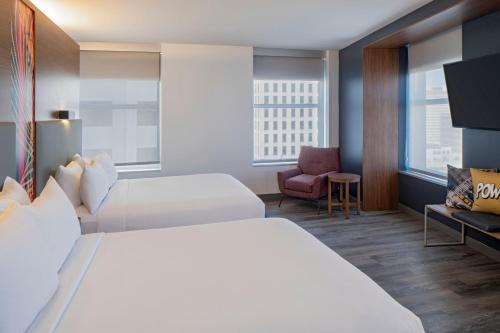 a hotel room with two beds and a chair at Aloft New Orleans Downtown in New Orleans